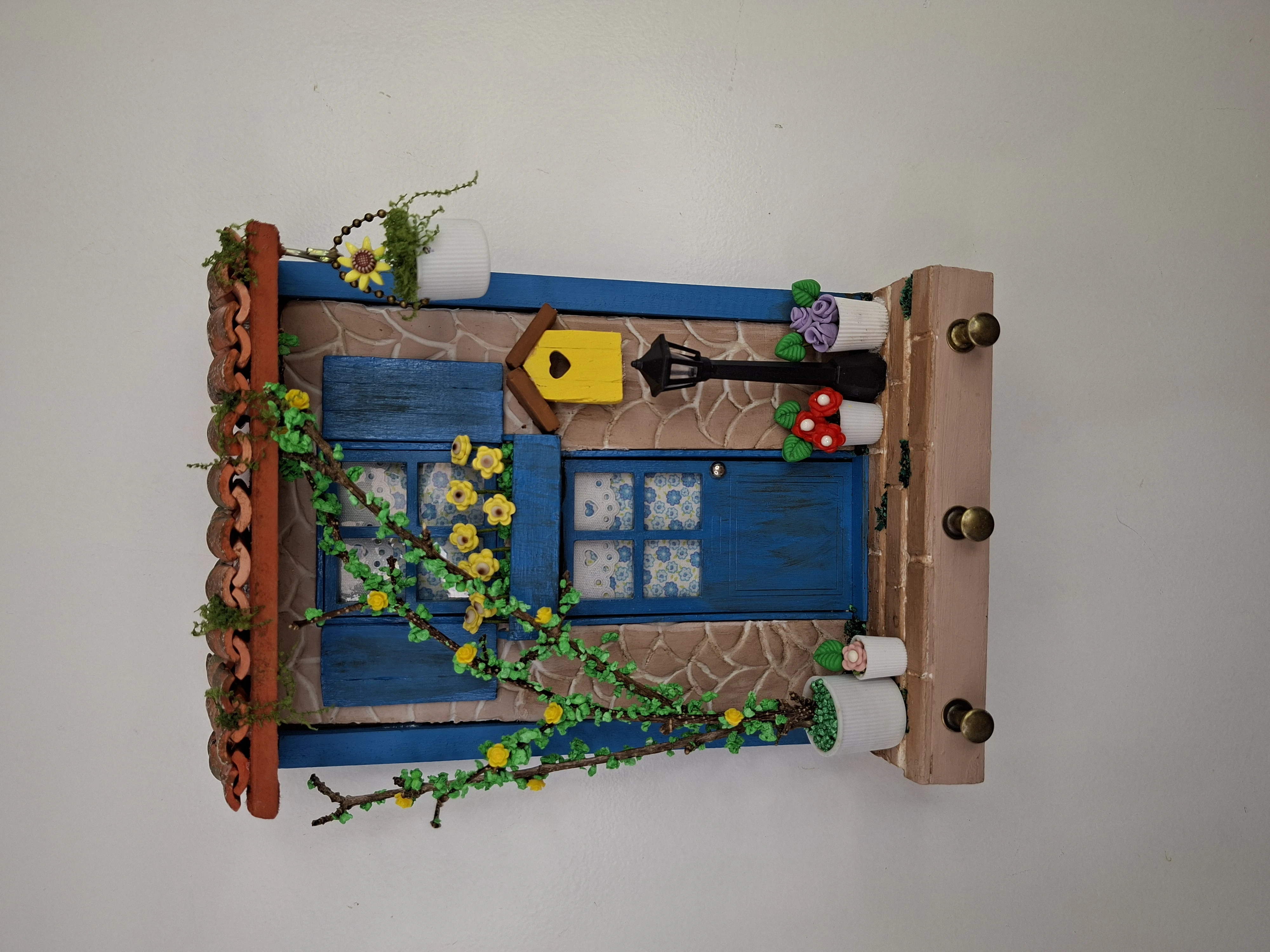 Porta chave de madeira ocre e azul frente de casa decorado com miniaturas