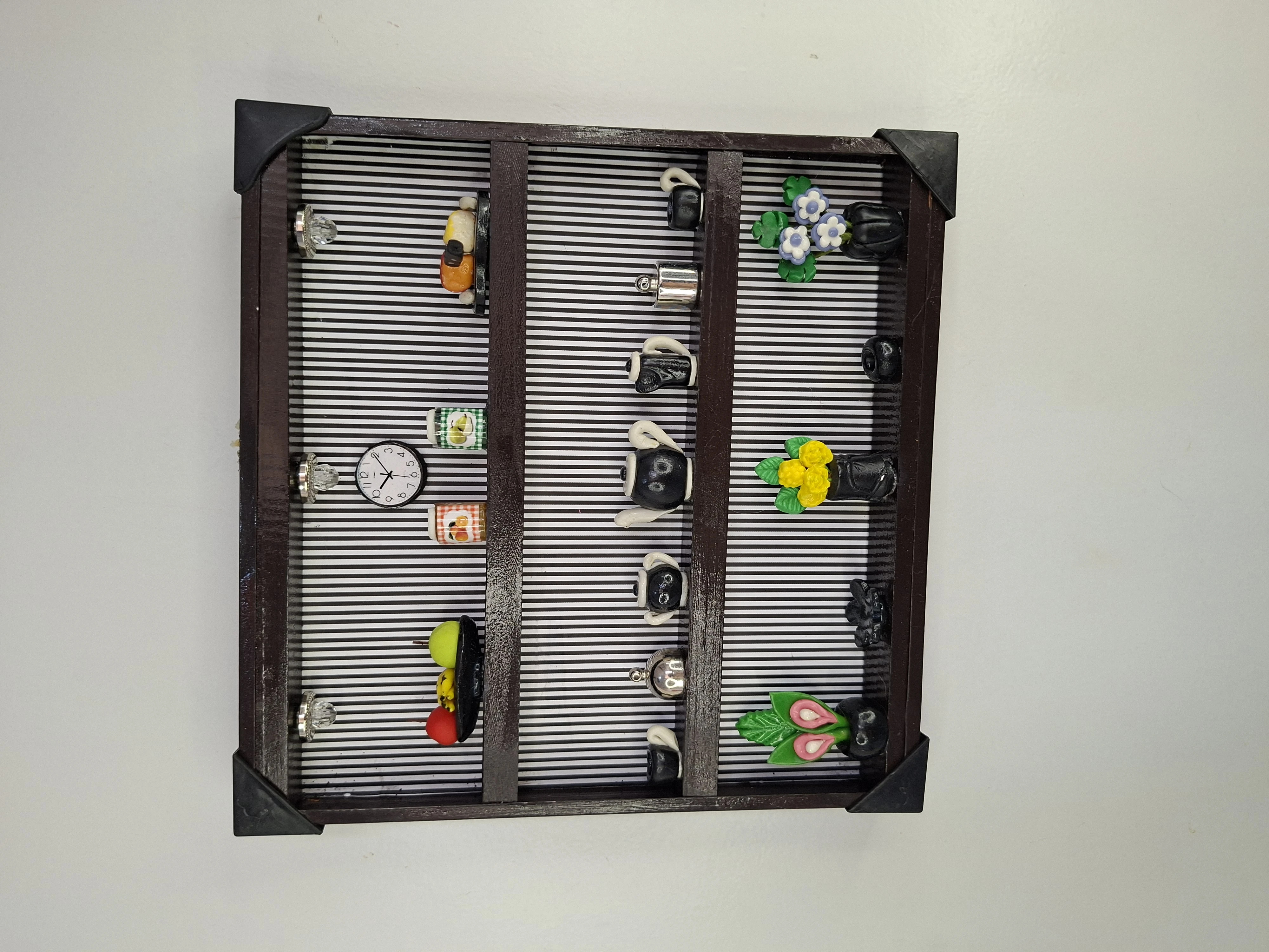 Quadro de ferro preto com fundo listrado decorado com miniaturas